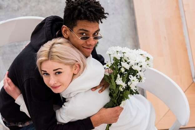 man holding flowers behind back of woman he is embracing man holding flowers behind back of woman he is embracing
