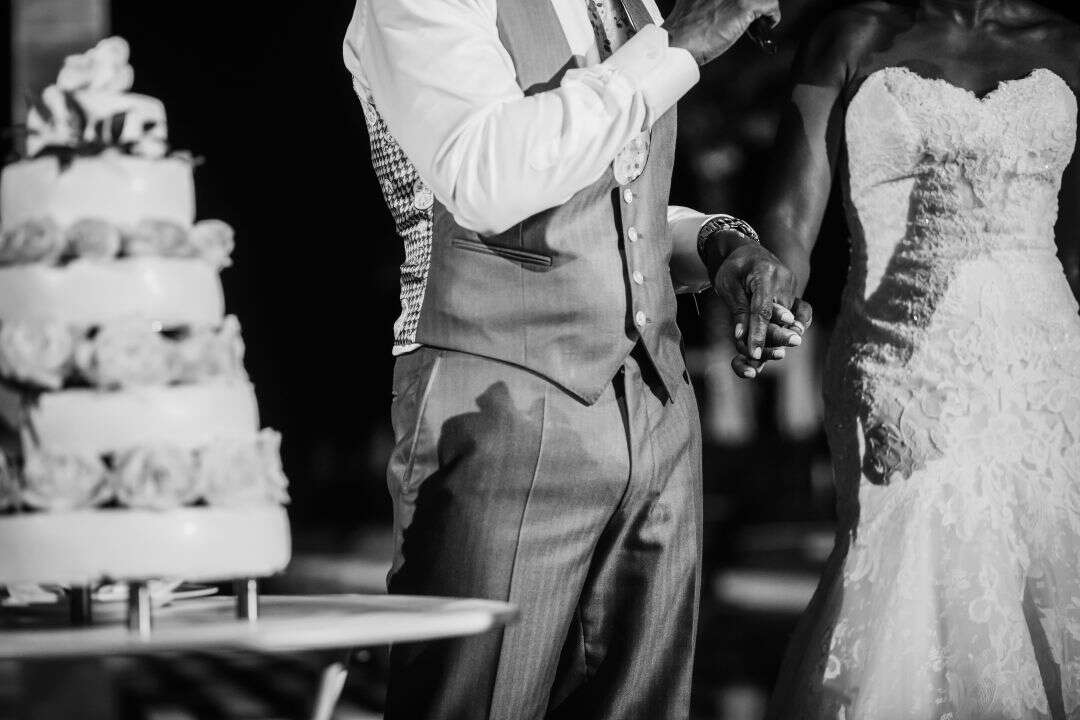 bride and groom hold hands next to wedding cake